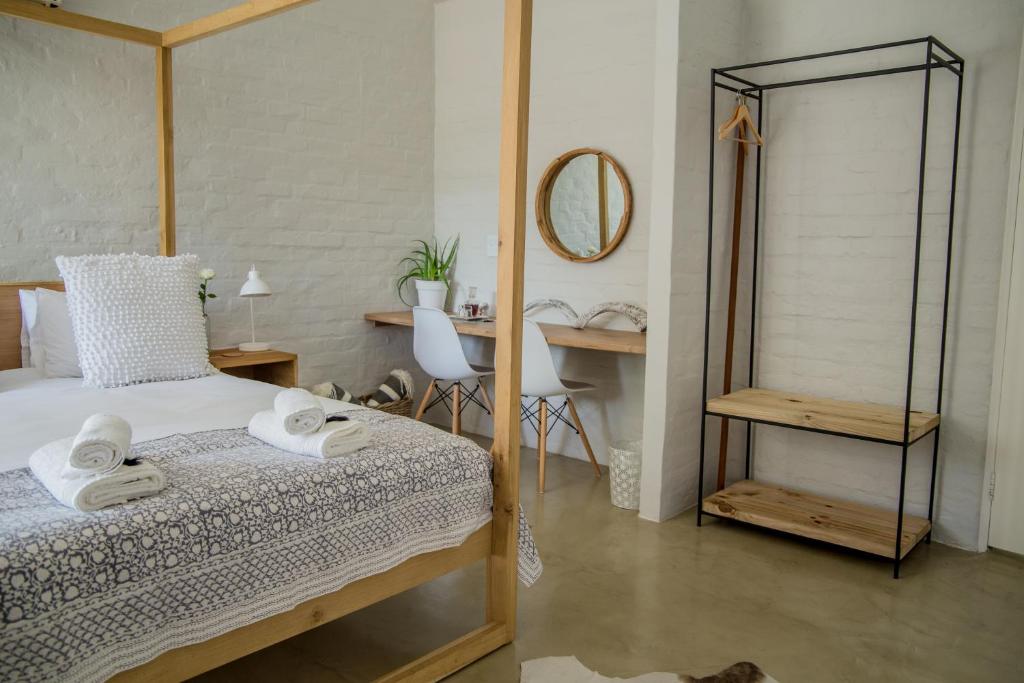 奥茨胡恩Raw Karoo Guest House的一间卧室配有一张床、一张书桌和一面镜子