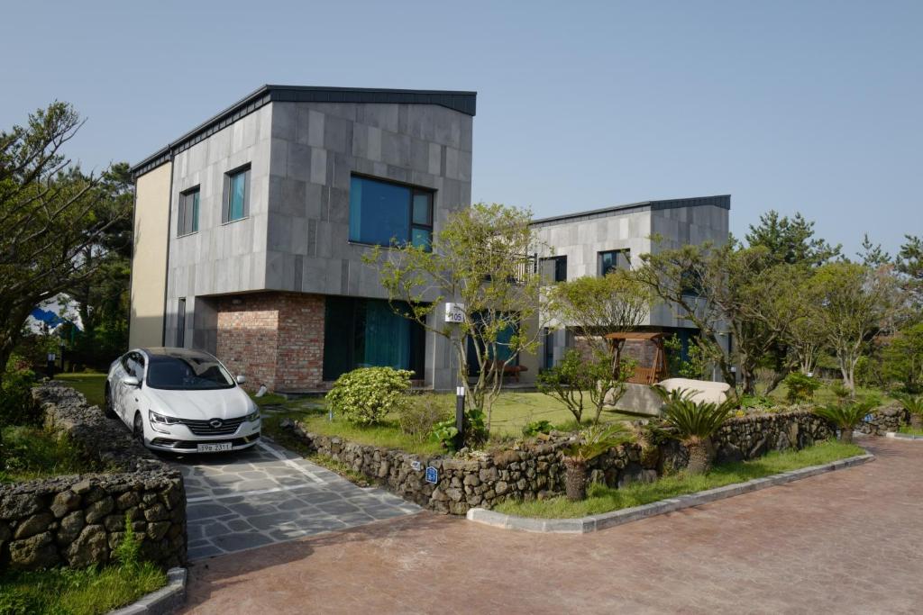 济州市Jeju TheRiche Pension的停在房子前面的汽车