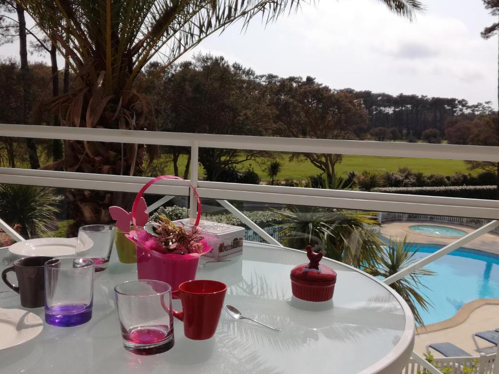 莫列马阿Location d Armelle - Moliets的阳台上配有带玻璃杯和鲜花的白色桌子