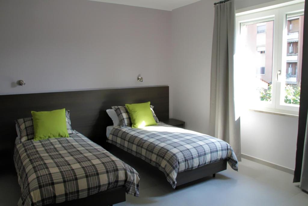 弗罗西诺内EasyRoom Frosinone - Casello Autostradale的一间卧室配有两张带绿色枕头的床和窗户。