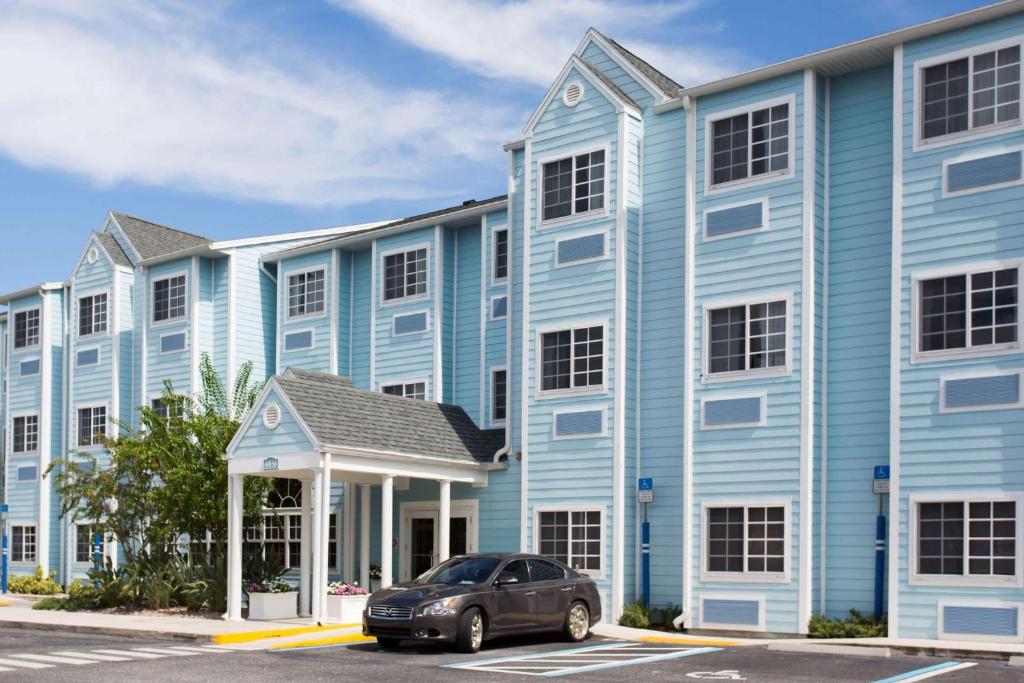 夏洛特港Microtel Inn & Suites by Wyndham Port Charlotte Punta Gorda的停在蓝色建筑前面的汽车