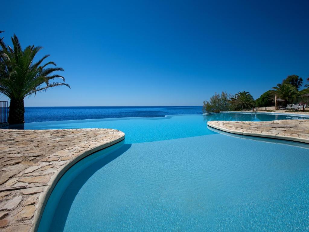 圣玛格利特迪普拉迪菲奥里海岸酒店的一座拥有蓝色海水和棕榈树的游泳池