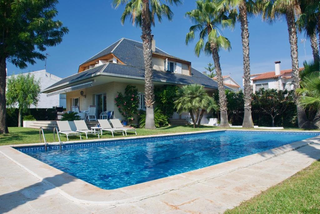 托里代巴拉Villa Cala de la Mora的棕榈树屋前的游泳池