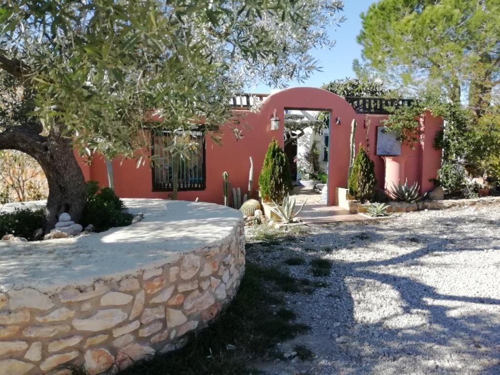 卡马尔莱斯Casa Rural Delta del Ebro Ecoturismo的一座红色的房子,有石墙和一棵树