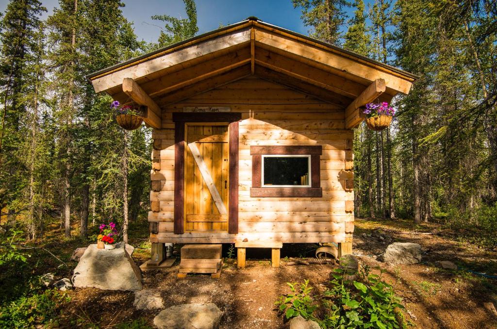 McCarthyBlackburn Cabins - McCarthy, Alaska的树林中的小木舱,花卉盛开