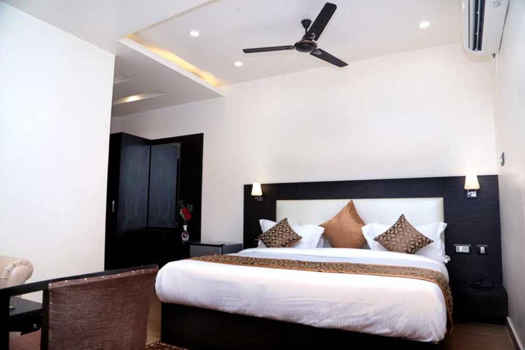 勒克瑙Hotel Vinayak Lifestyle Hotels的一间卧室配有一张大床和吊扇