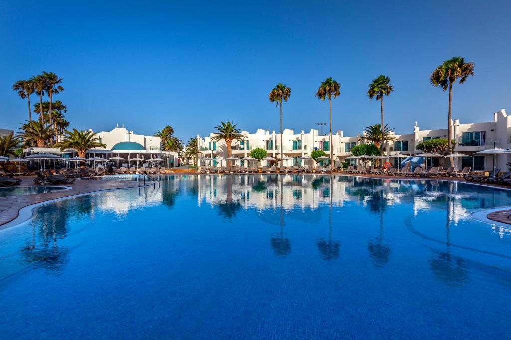 科拉雷侯科拉莱霍巴塞罗沙滩酒店的一座棕榈树和建筑的大型游泳池