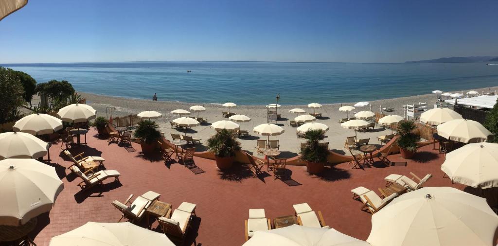瓦里格提Miramare di Varigotti的海滩上设有白色的遮阳伞和椅子,还有大海