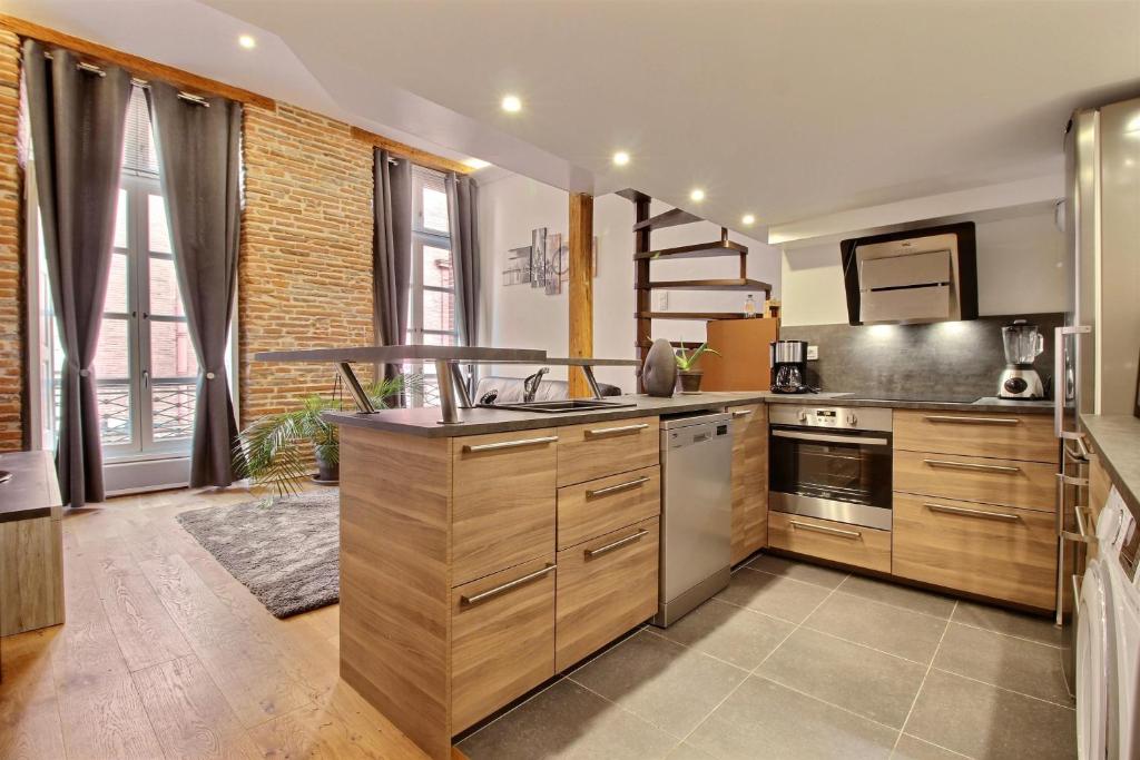 图卢兹TOULOUSE DUPLEX PLACE DU CAPITOLE的厨房配有木制橱柜和不锈钢用具