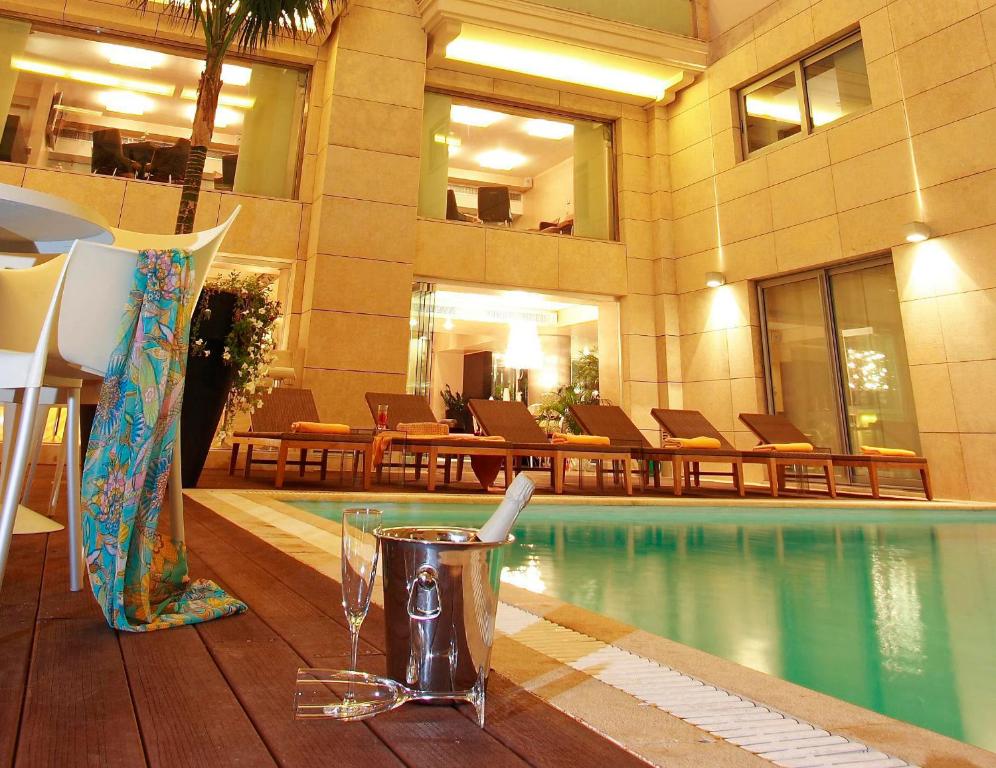 纳弗帕克托斯纳弗斯酒店的一间设有游泳池的酒店,并在餐桌上喝一杯