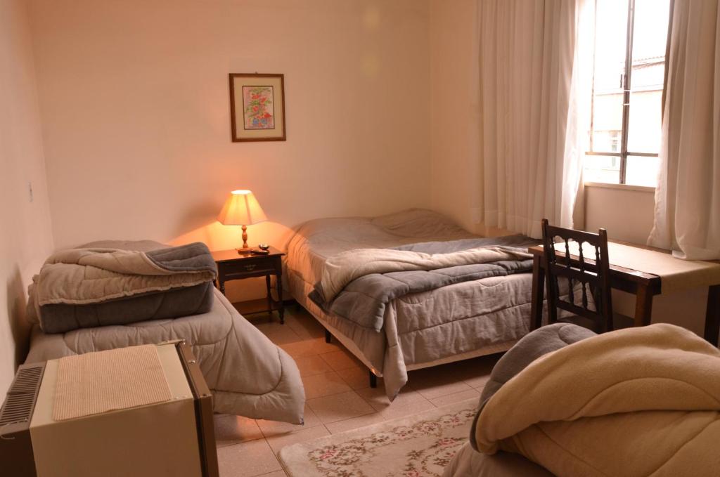 圣若阿金Hotel Maristela的一间卧室设有两张床、一张桌子和一个窗口