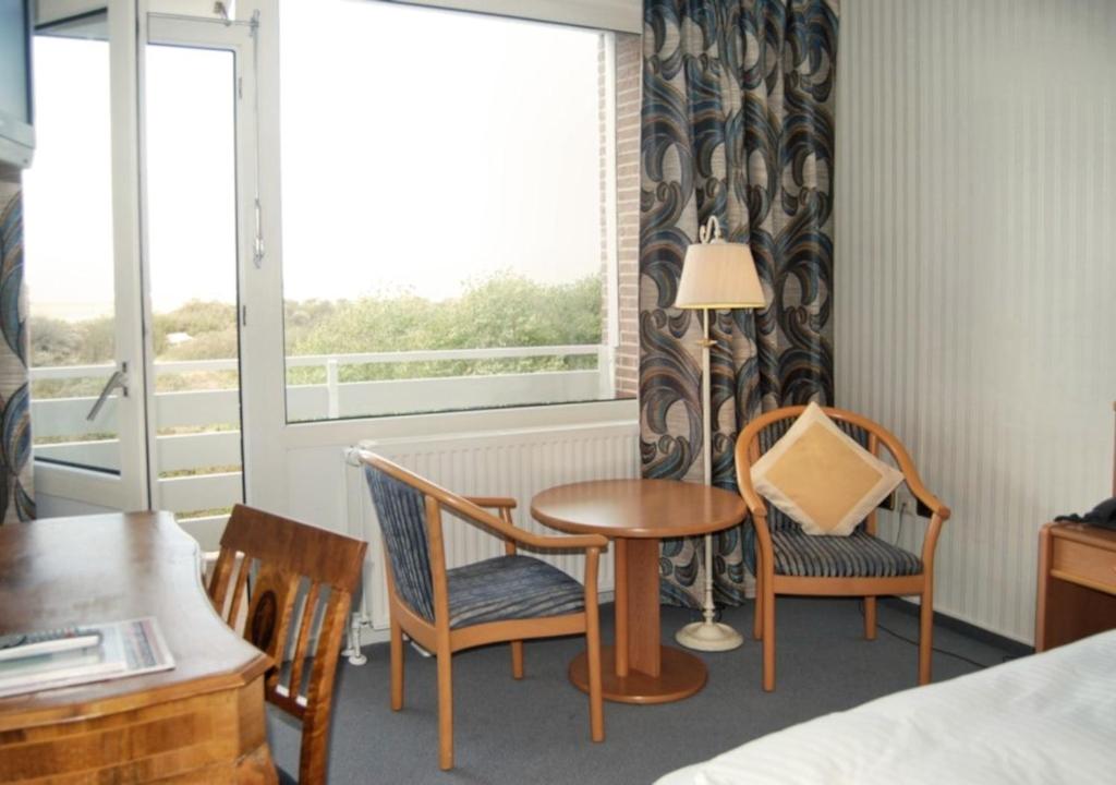 博尔库姆Hotel das Miramar的客房设有桌椅和窗户。