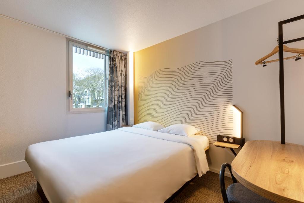 里尔B&B HOTEL Lille Centre Grand Palais的卧室配有一张白色的大床和一张桌子