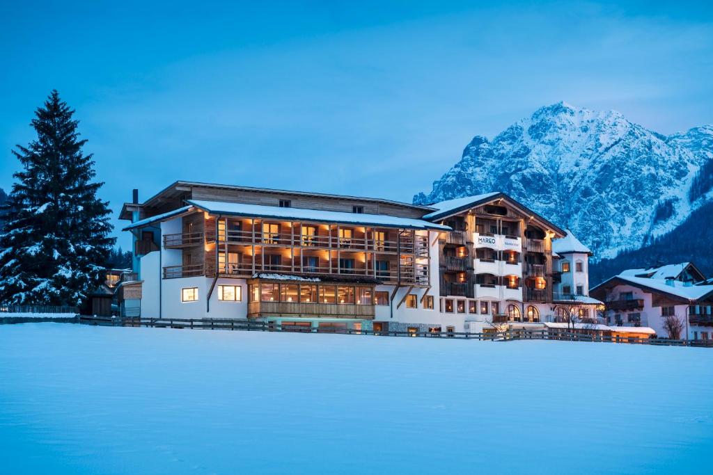 圣维吉利奥Hotel Mareo Dolomites的山前有积雪的大建筑