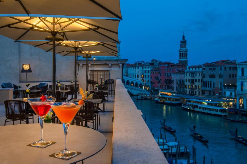 威尼斯H10 Palazzo Canova的一张桌子上放两个鸡尾酒,享有运河的景色