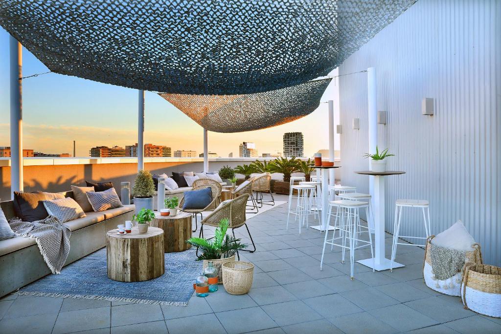 巴塞罗那Hotel Barcelona Condal Mar Affiliated by Meliá的屋顶庭院配有沙发和桌椅