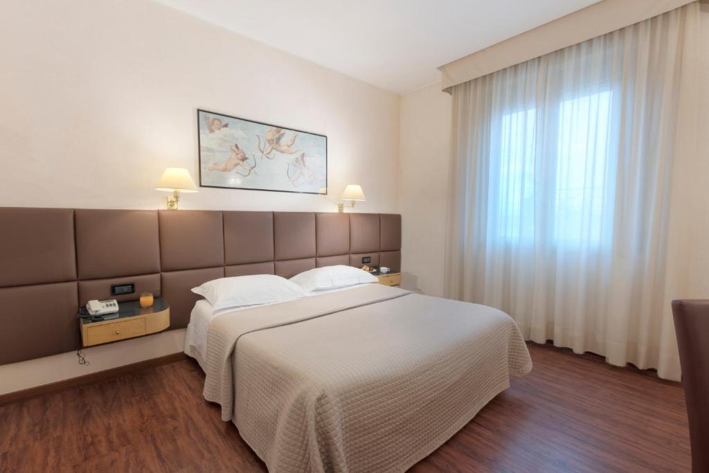 阿雷佐米尼尔瓦酒店的卧室设有一张白色大床和一扇窗户。