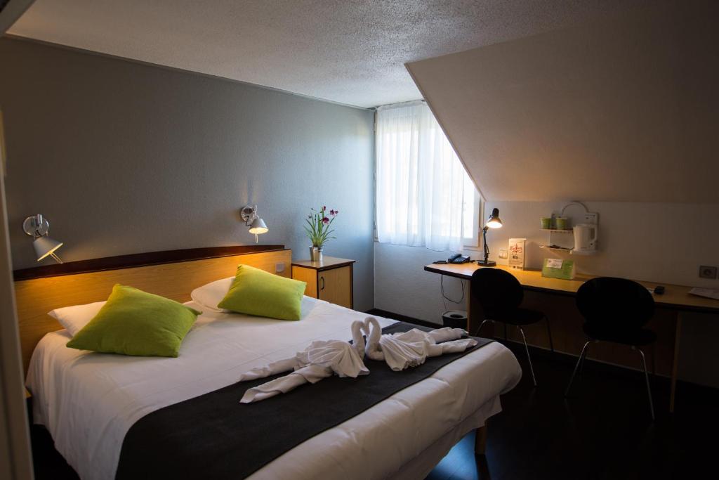 索米尔索米尔钟楼酒店的一间卧室配有一张带绿色枕头的床和一张书桌
