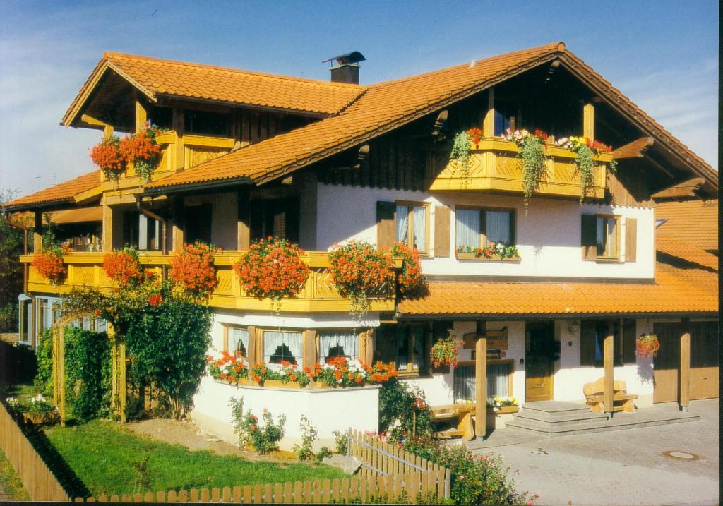 内森尔旺Gästehaus Kerpf inclusive KönigsCard的一座黄色的大房子,窗户上有鲜花