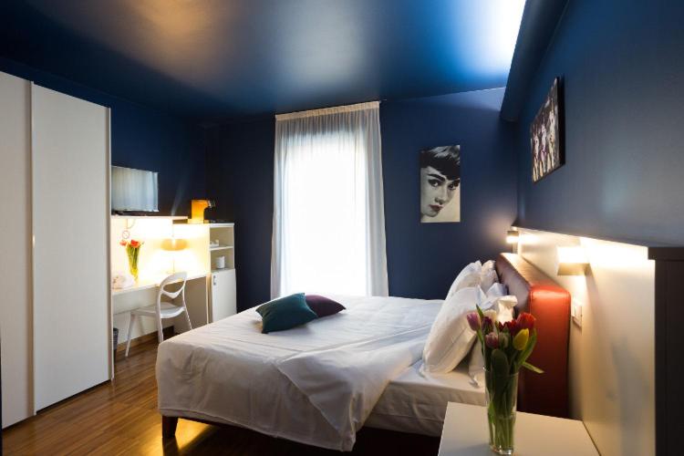 乌迪内Albergo Residenza Al Teatro的蓝色的卧室,配有一张带花瓶的床