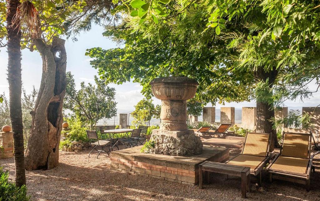 加沃拉诺Il Castello Gavorrano的庭院里的喷泉,有椅子和树木