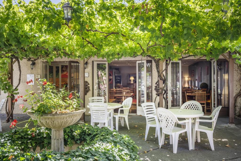 阿维尼翁克里斯托酒店的树下带桌椅的庭院