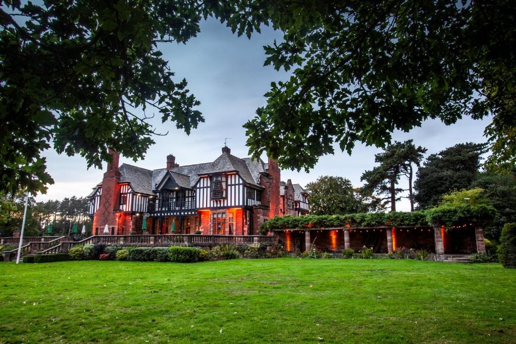 莱德沙姆英格伍德庄园酒店的一座古老的房子,前面有一片绿色的草坪