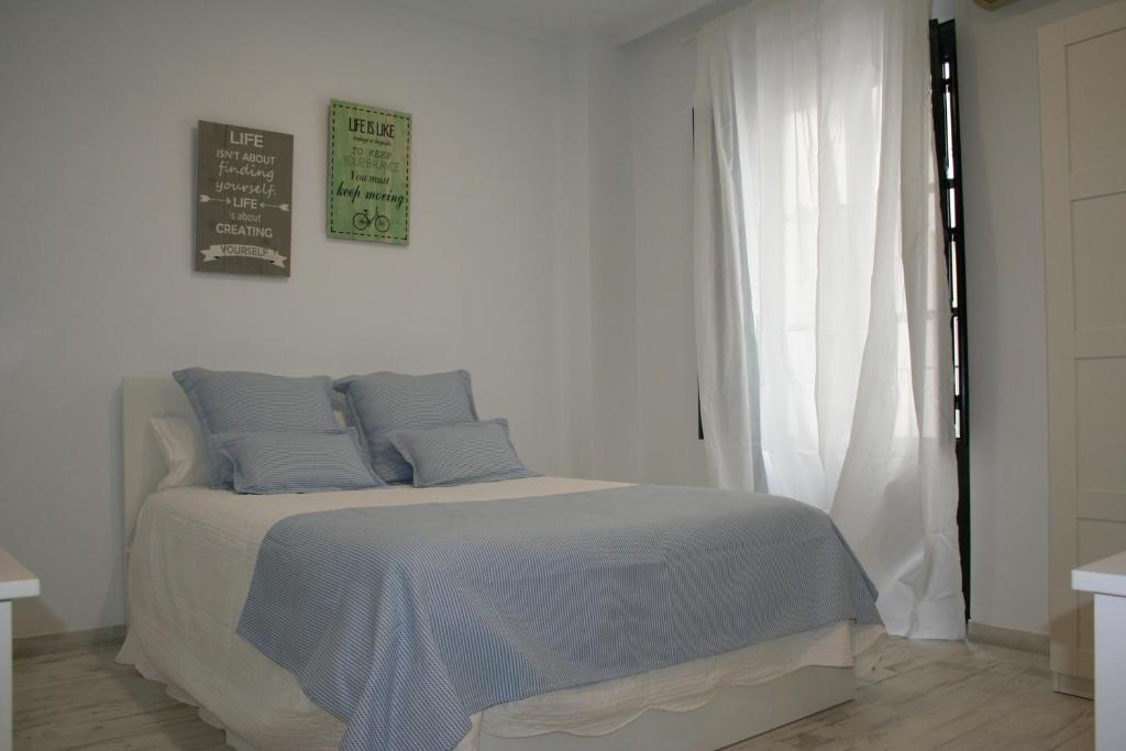 塞维利亚CLB Sierpes Apartment的白色卧室配有蓝色枕头的床