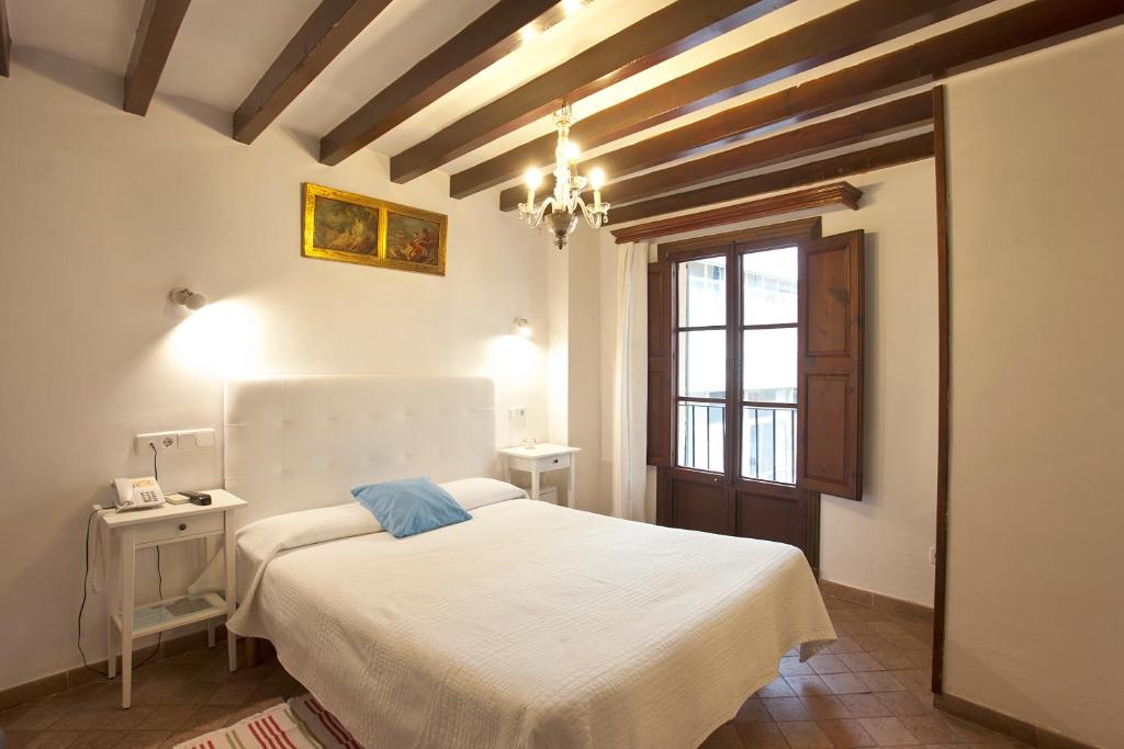 马略卡岛帕尔马图瑞莫迪因特卡萨帕迪瑞娜酒店的卧室配有白色的床和吊灯。