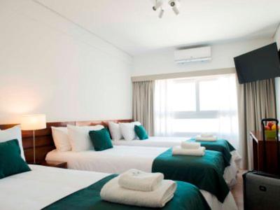 布宜诺斯艾利斯Hotel 6 de Octubre的一间卧室配有三张床,铺有绿色和白色的床单