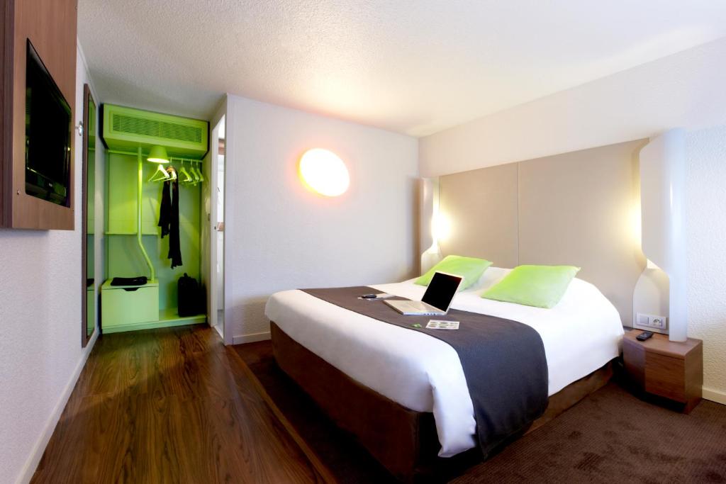 巴约讷钟楼巴永娜酒店的一间卧室配有一张大床,上面有笔记本电脑