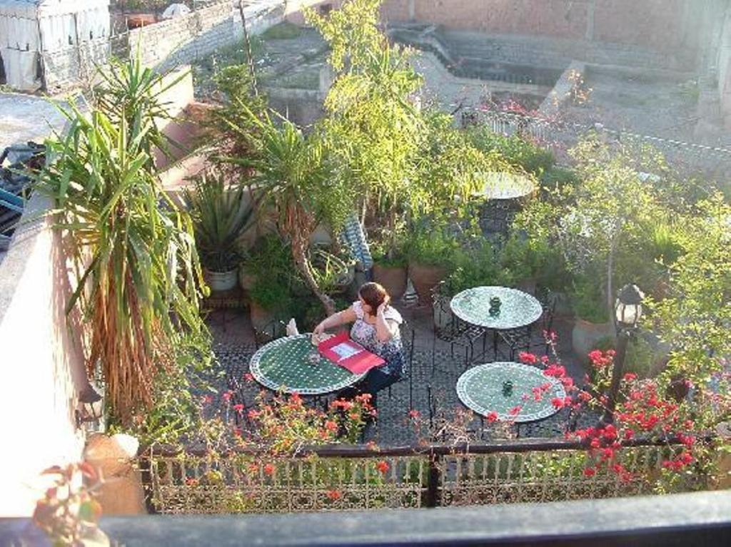 马拉喀什Riad Hôtel Belleville Marrakech的坐在花园桌子上的女人
