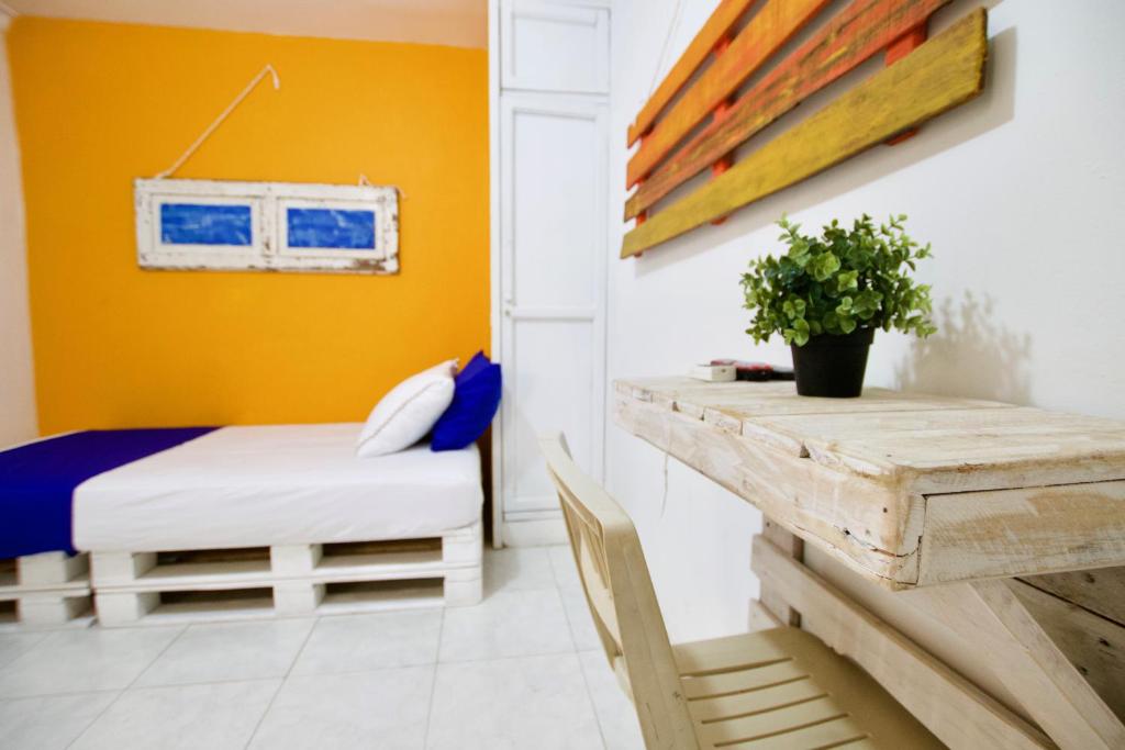 巴兰基亚QuillaHost Guesthouse的一间卧室配有一张床、一张桌子和一张长凳