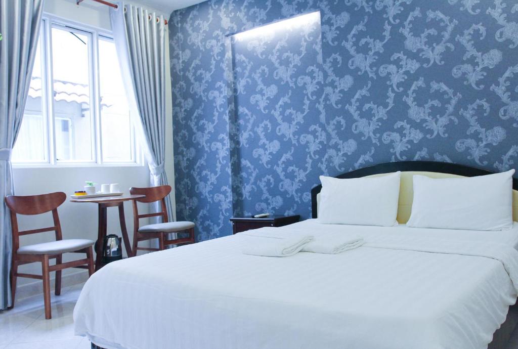 胡志明市紫罗兰星级酒店及Spa的一间卧室配有一张床和一张桌子及椅子