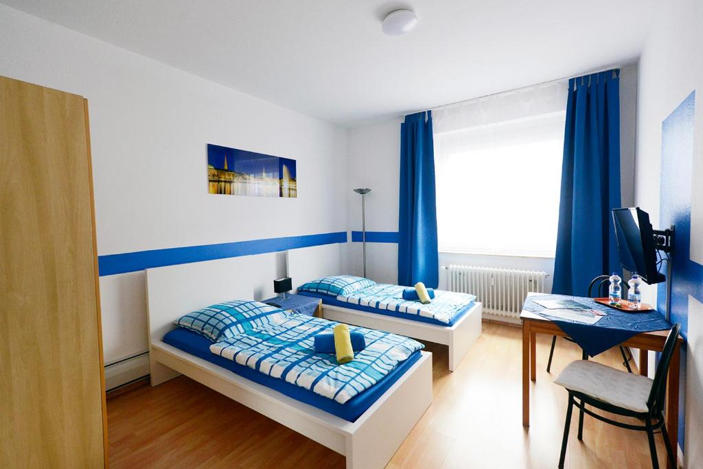 汉堡库奇加藤地下室旅馆的配有两张床铺的蓝色窗帘和书桌