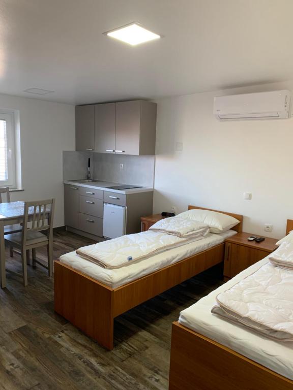 马里博尔Apartman Decorus的带两张床和一张桌子的房间以及一间厨房