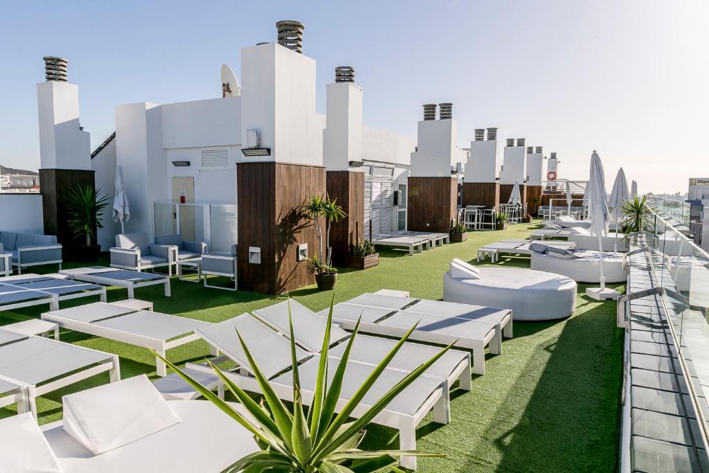 大加那利岛拉斯帕尔马斯Exe Las Palmas的屋顶上设有白色椅子和桌子的屋顶露台