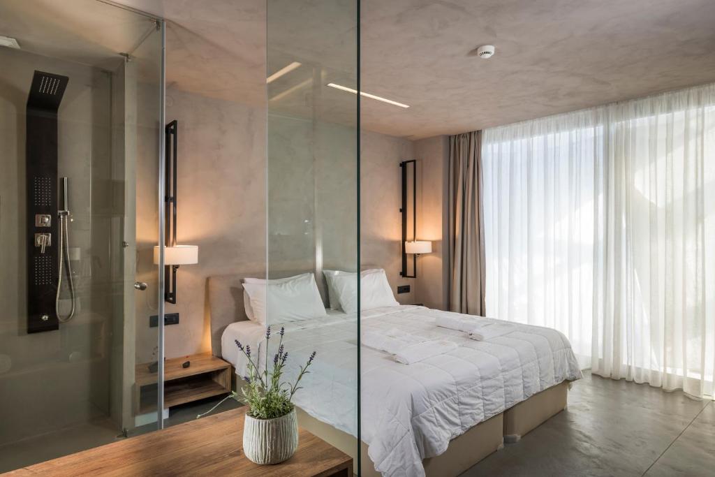 卡拉马基Icarus Hotel的一间卧室设有一张床和一个玻璃淋浴间