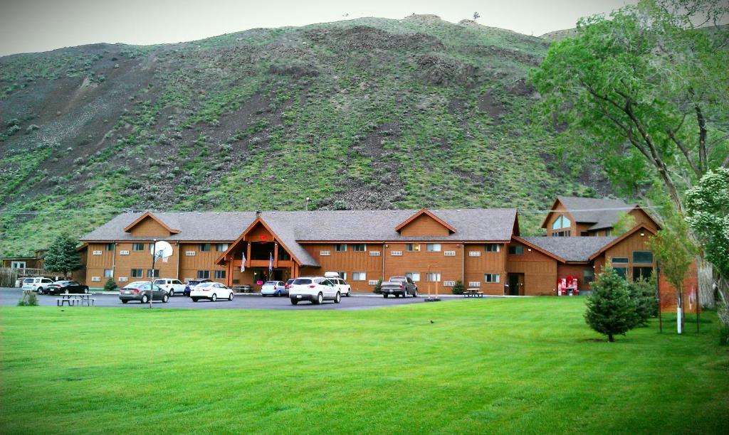 加德纳Yellowstone Village Inn and Suites的一座大建筑,有汽车停在山前