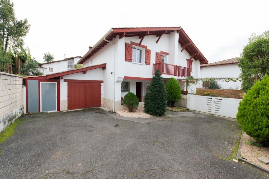 昂代Hermosa casa con terraza y jacuzzi en Hendaya的白色的房子,有红色车库