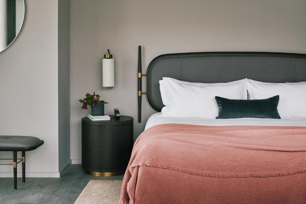 伦敦The Stratford Hotel London的一间卧室配有一张带红色毯子和桌子的床。