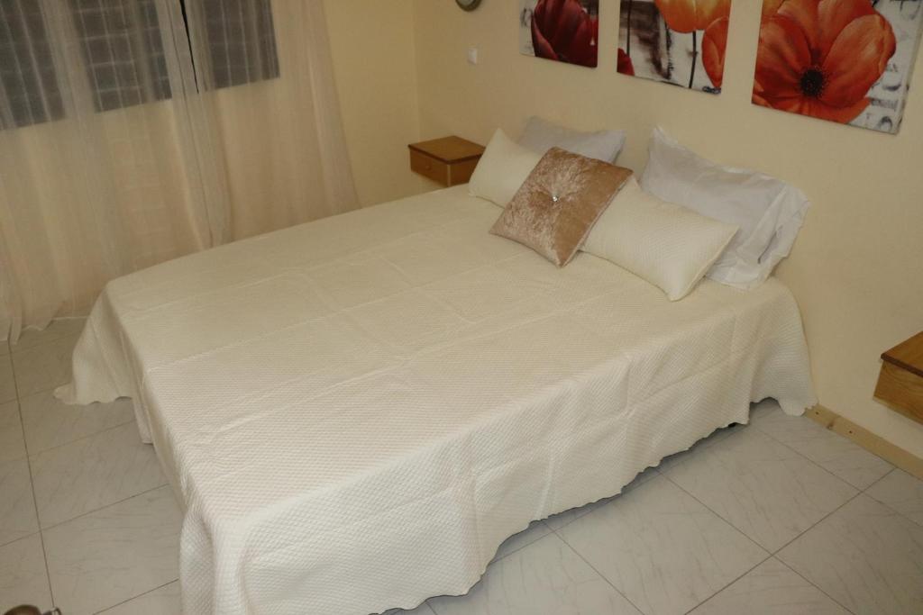 埃斯帕戈斯Apartamento Preguiça的一张带白色床单和枕头的床