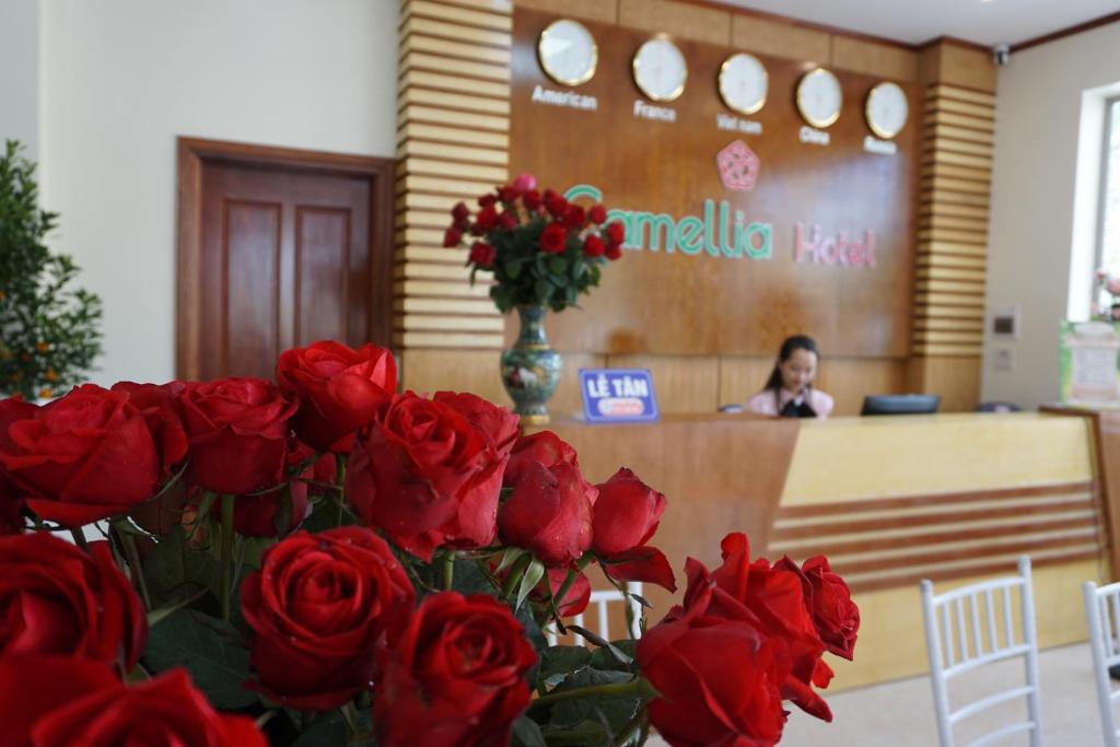 清化Camellia Hotel的坐在桌子前的红玫瑰花瓶