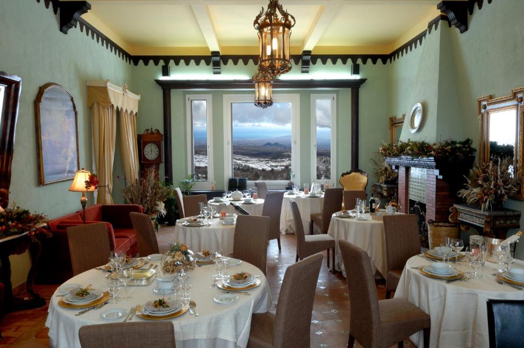 尼科洛西多拉塔别墅酒店的餐厅配有白色的桌椅和吊灯