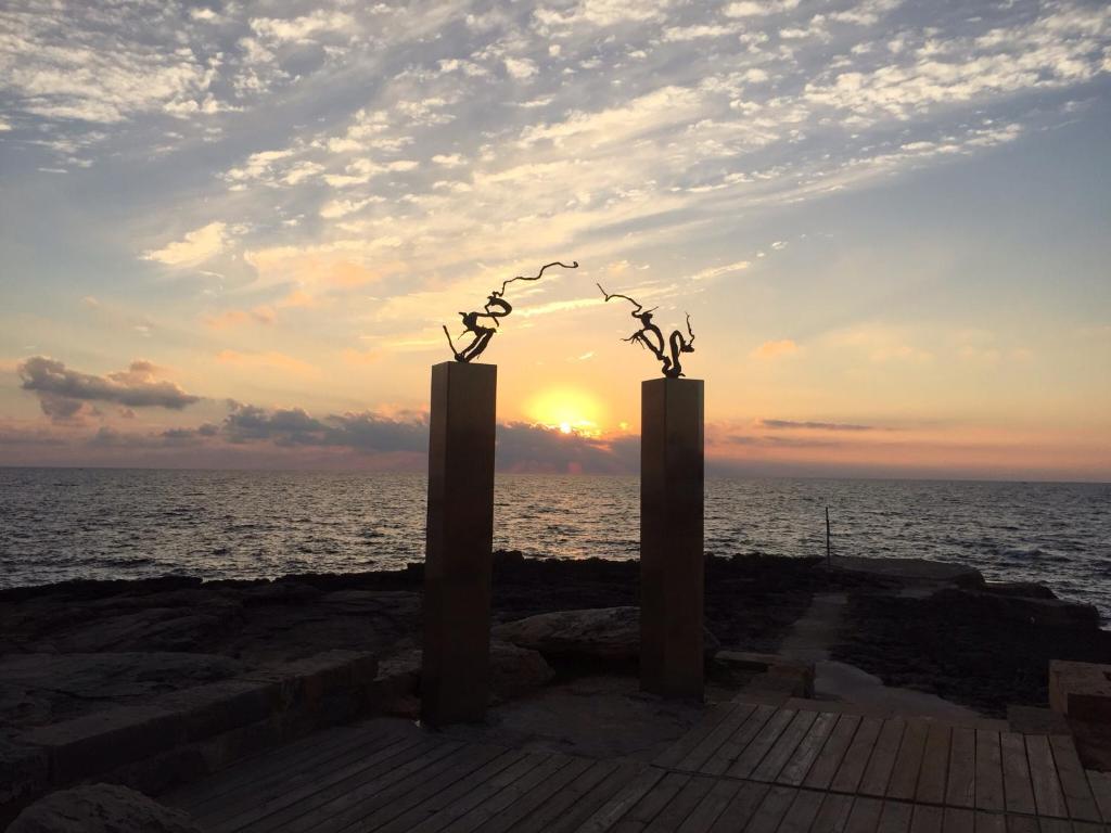 科洛尼亚圣霍尔迪Holiday beach homes Romaní II的码头上的两个雕塑,背景是日落