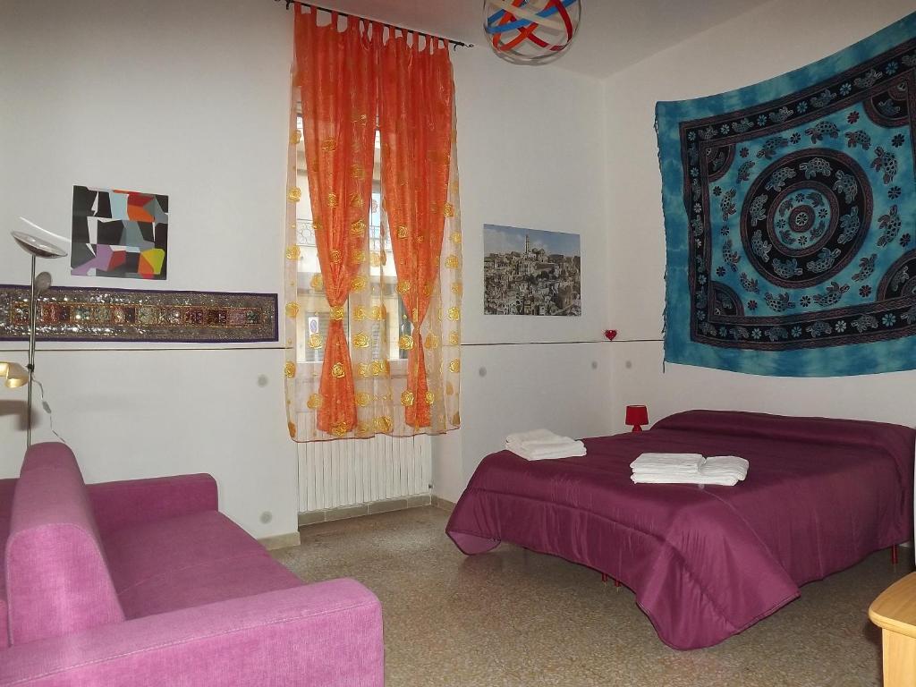 马泰拉Casa Vacanze La Terra dei Briganti的一间卧室配有一张紫色的床和一张沙发