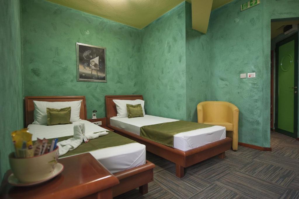 波德戈里察可贝尔酒店的绿墙和桌子的客房内的两张床