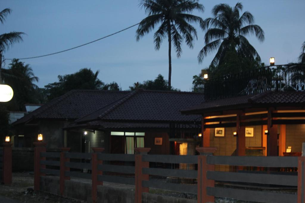 巴图卡拉亚马逊简易别墅&小屋假日公园的夜间有围栏和棕榈树的房子