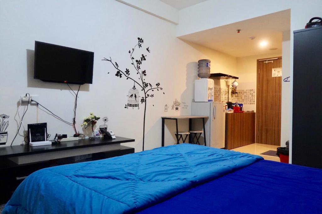 万隆Bacup Studio Apartment @Galeri Ciumbuleuit的一间卧室配有蓝色的床、一张书桌和一台电视。