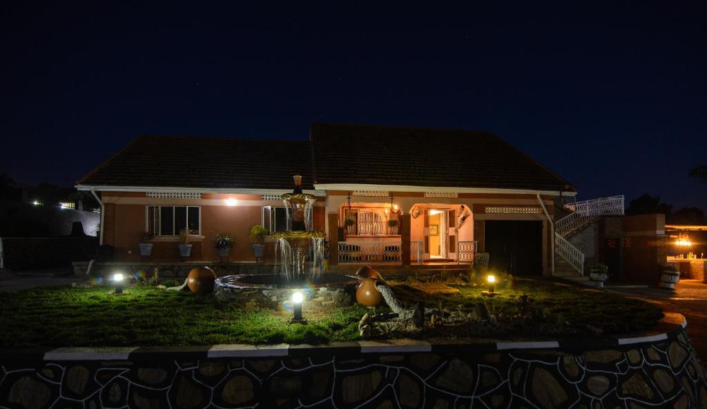 恩德培Lake Victoria Country Home的一座房子,在晚上有喷泉在前面